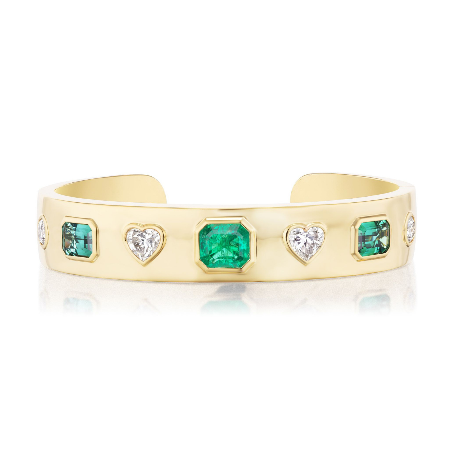 Bezel Set Mixed Shape Diamond and Emerald Bangle in Yellow Gold features alternating rectangular emeralds and heart-shaped diamonds, all elegantly set in luxurious 18K yellow gold and displayed against a white background.