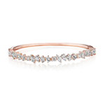 The Marching Mixed Shape Diamond Bangle is a rose gold bracelet crafted from 18K gold and embellished with a dazzling assortment of clear diamonds—featuring striking emerald cut VS clarity stones—arranged in an artfully jagged pattern along the top half of the band, shown on a white background.