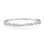Introducing the Marching Mixed Shape Diamond Bangle: a silver bracelet showcasing an elegant arrangement of clear gemstones in assorted shapes, including dazzling emerald cut diamonds with VS clarity, clustered gracefully along the front.
