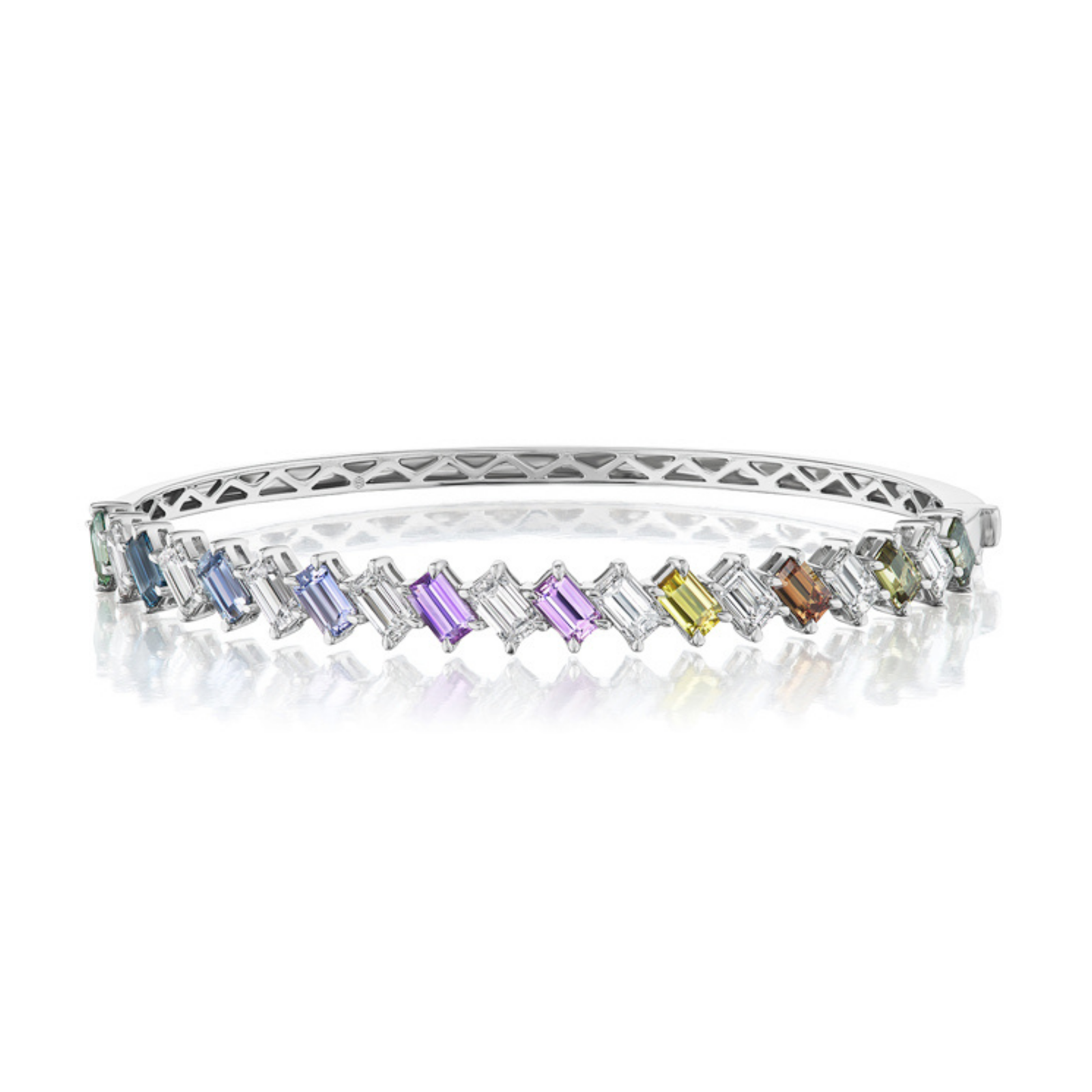 The Marching Emerald Cut Diamond and Multicolor Sapphire Bangle in White Gold showcases alternating rectangular gemstones—vivid emerald-cut sapphires in blue, green, purple, yellow, and clear hues—radiantly displayed on a reflective surface.
