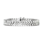 Introducing the Half-Bezel Set Chevron Diamond Tennis Bracelet in White Gold—a stunning piece featuring a sleek, modern chevron pattern crafted from luminous white gold. Rectangular links are arranged in a repeating zigzag design, their polished and reflective surfaces creating an elegant shine. Rows of baguette diamonds accent each link, adding sophisticated brilliance and elevating this bracelet’s refined aesthetic.