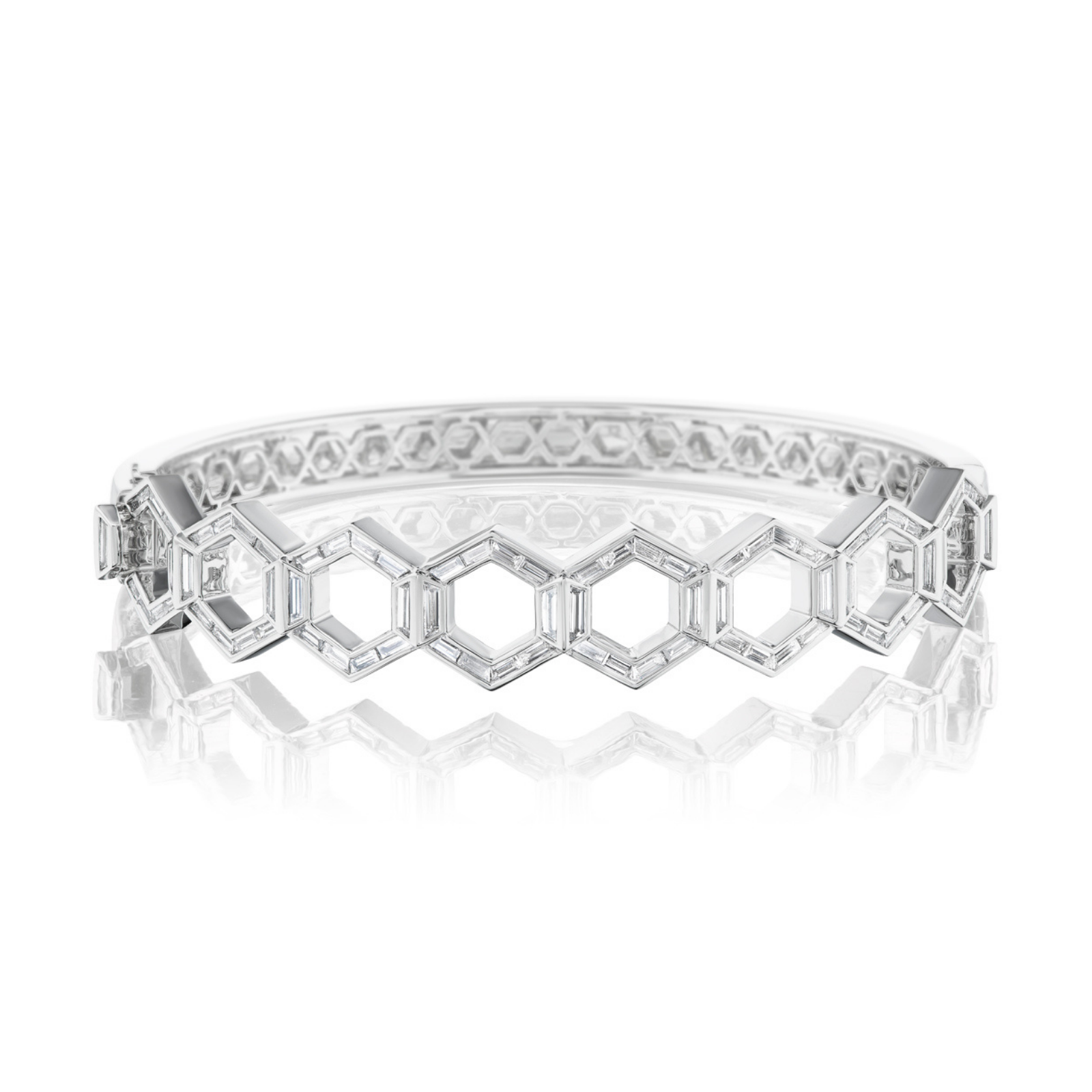 The Chrysler Hexagon Bangle with Baguette Diamonds is a silver bracelet showcasing a geometric hexagon pattern inspired by the iconic design, adorned with clear gemstones and exquisite baguette diamonds arranged in a honeycomb motif, displayed on a reflective white surface.