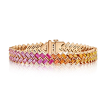 The Half Bezel Set Rainbow Sapphire Chevron Tennis Bracelet in Rose Gold, crafted in 18k rose gold and adorned with gradient baguette sapphires in pink, orange, and yellow hues arranged in a chevron pattern, is displayed on a white background.
