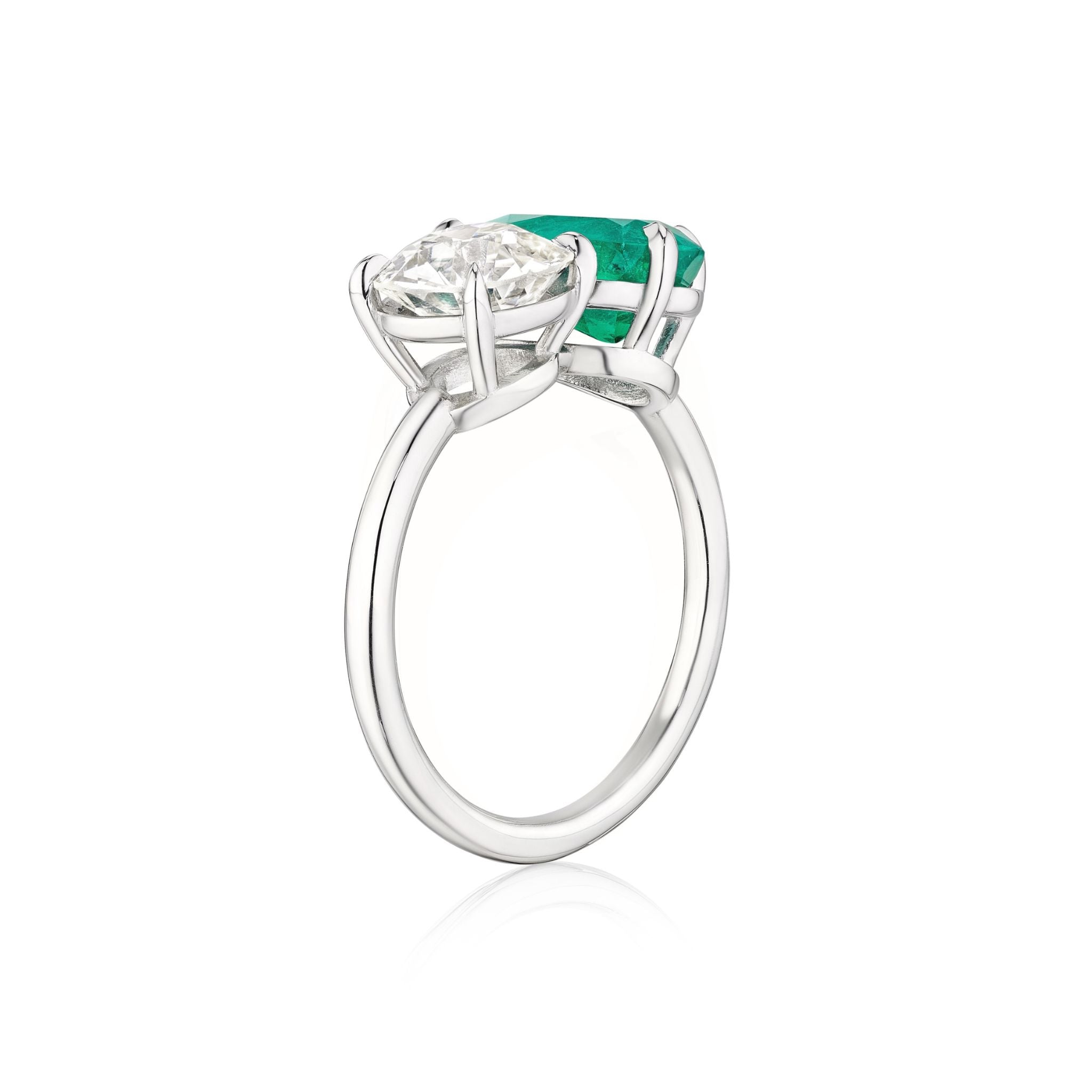 The Toi et Moi Pear Shape Emerald and Round Diamond Engagement Ring in White Gold showcases a pear-shaped emerald and a round diamond set side by side in elegant prongs against a white background.