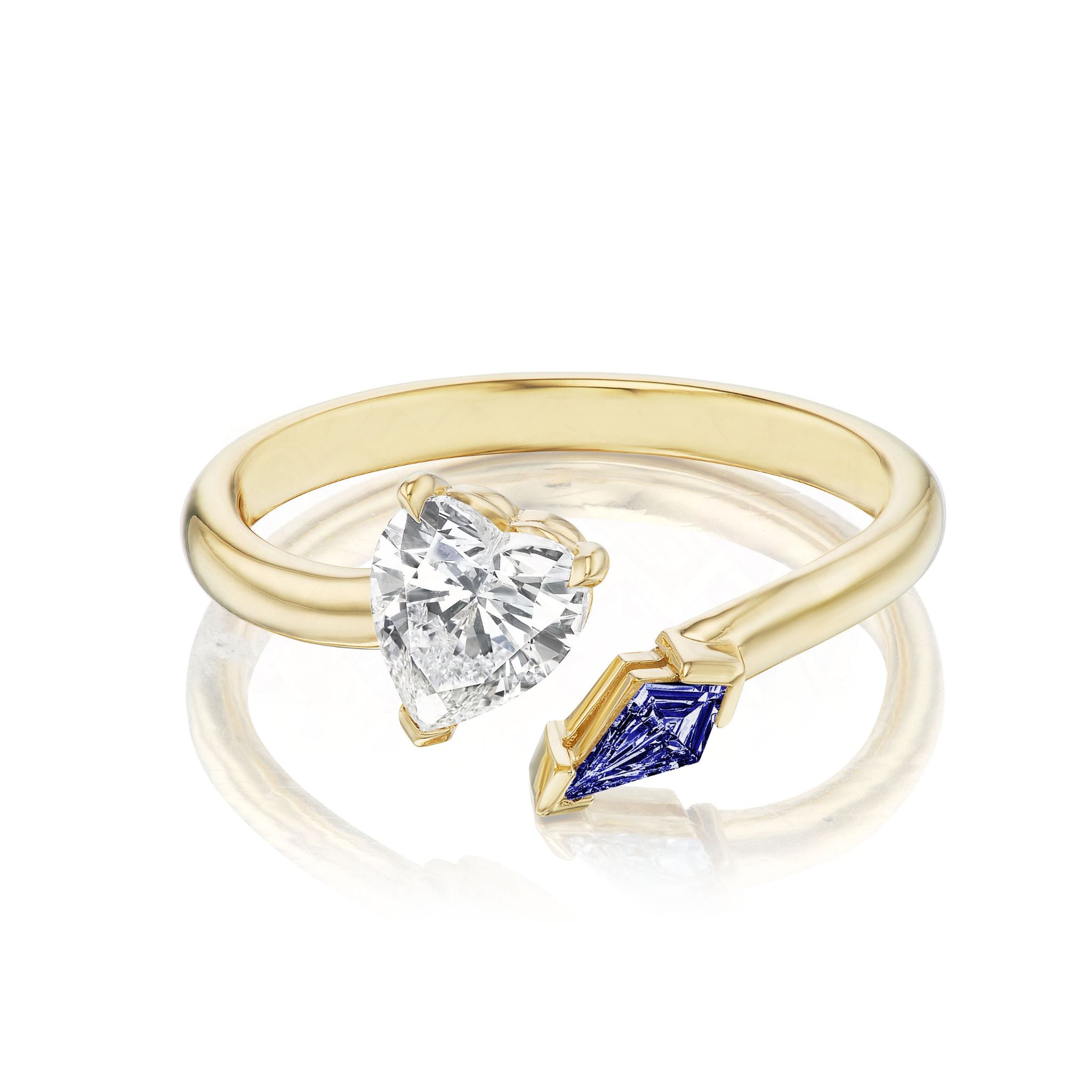 The Toi et Moi Ring features a heart shape diamond and a kite shaped sapphire set on opposite ends of an open 18K yellow gold band, displayed against a white background.