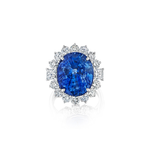 The Vintage Sapphire and Diamond Ring features an oval Ceylon sapphire encircled by a halo of round white diamonds, all set in an 18k white gold band and displayed on a white background.