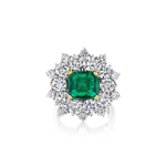 Presenting the Vintage Emerald and Diamond Ring, showcasing a striking, large square-cut Colombian emerald at its center, encircled by two rows of brilliant round white diamonds in an elegant floral design, all set on a polished platinum band.