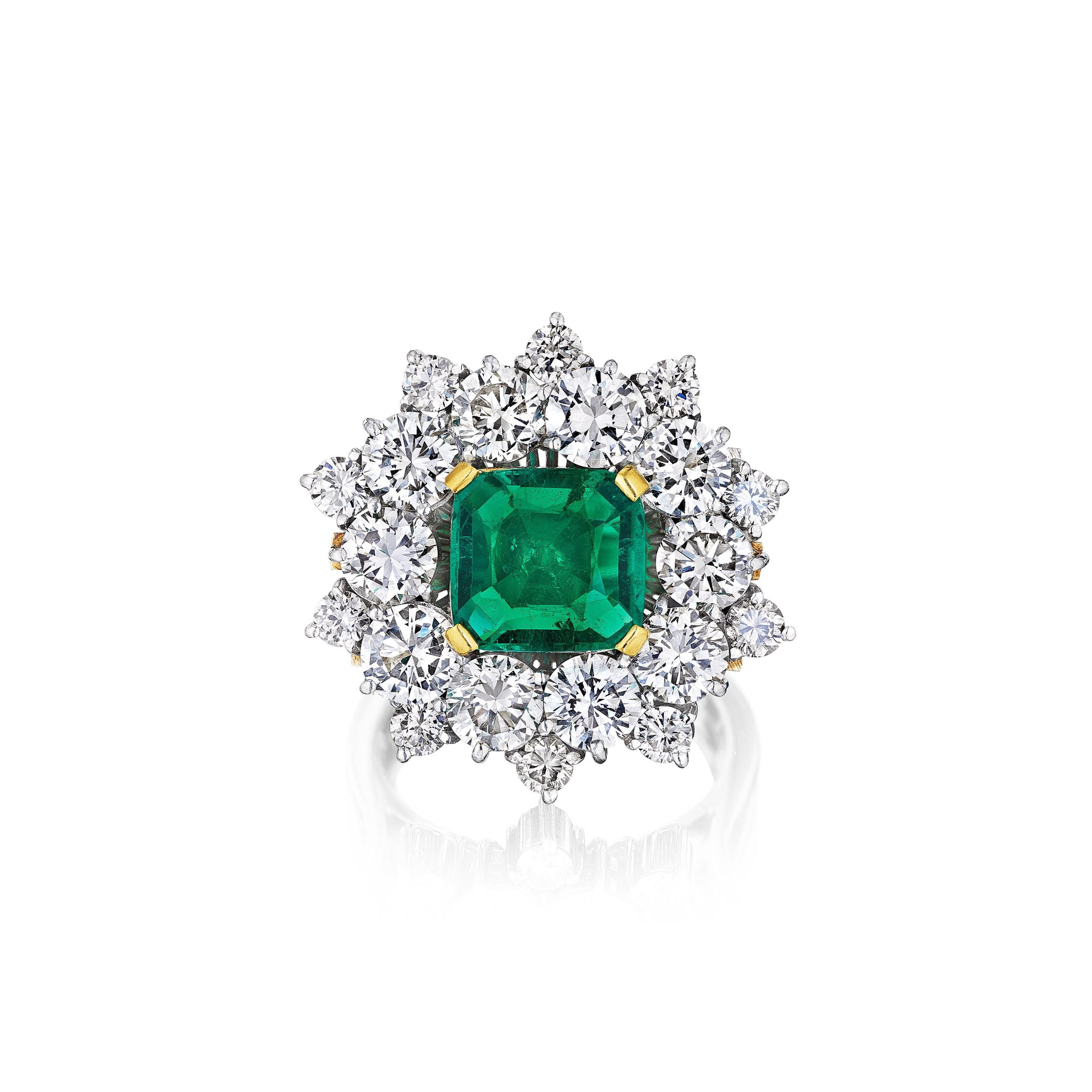The Emerald and Diamond Ring showcases a large square-cut Colombian emerald center, framed by round white diamonds in a starburst design on a polished platinum band.