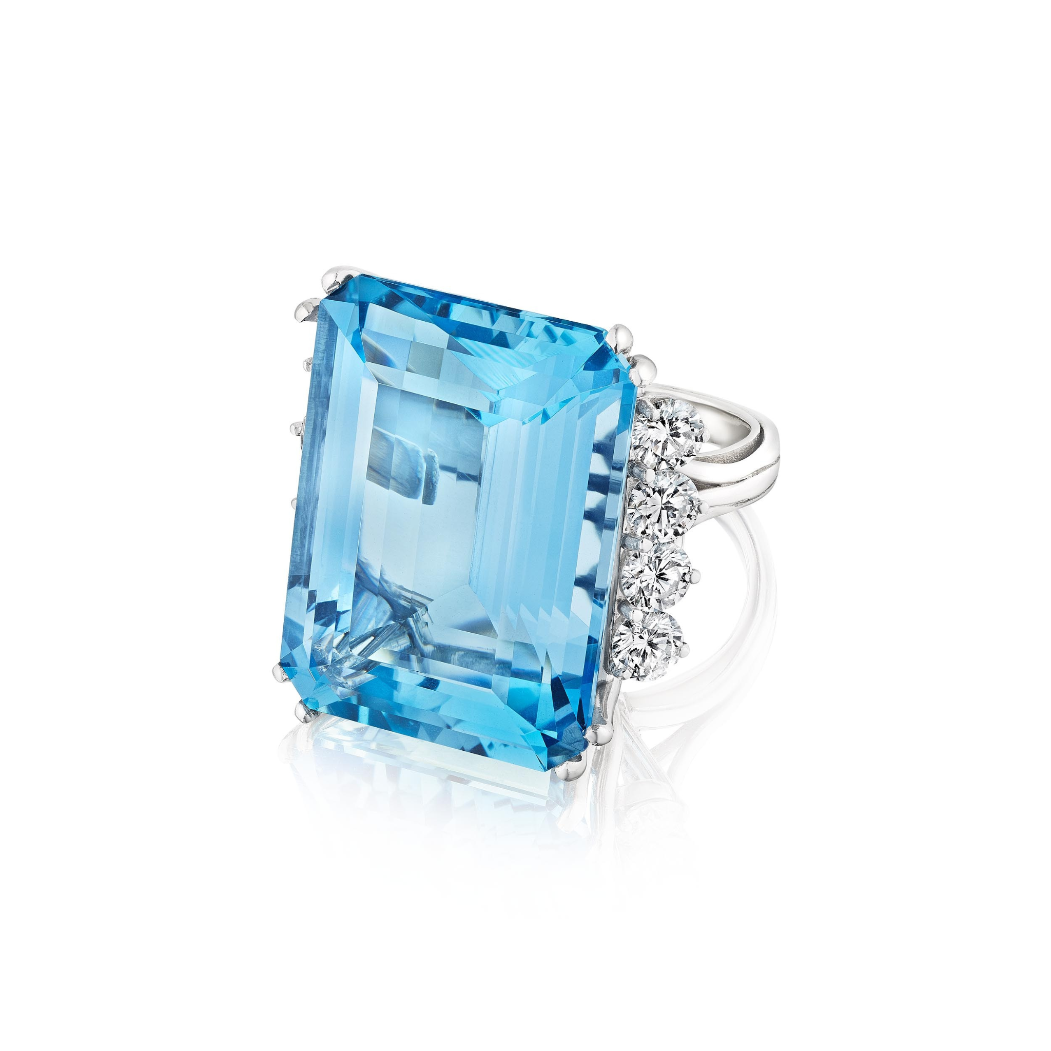 The Aquamarine and Diamond Ring features a platinum band with a large emerald-cut aquamarine and a cluster of round diamonds on one side, shown against a white background.