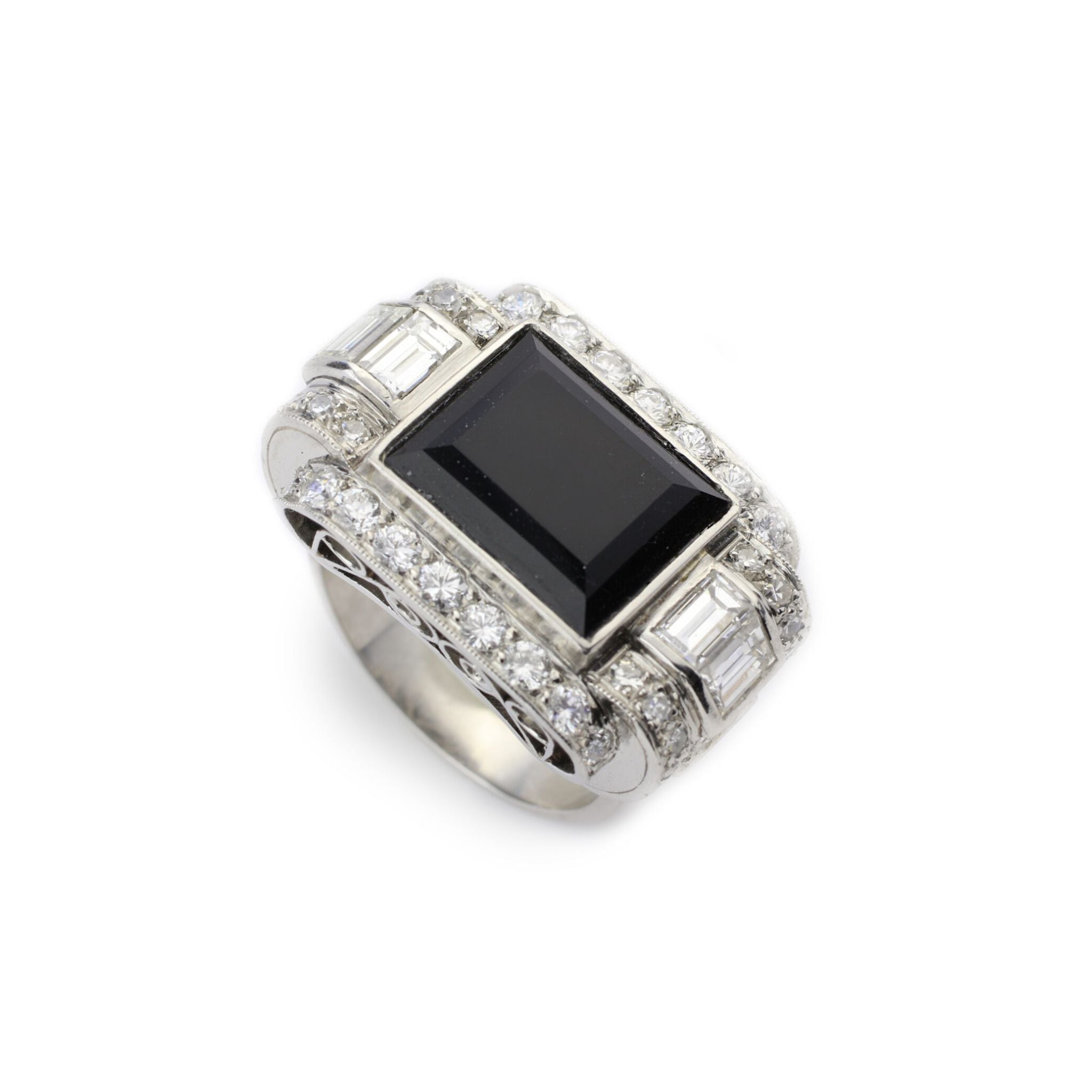 The Onyx and Diamond Ring features a large emerald-cut onyx center, surrounded by rows of round diamonds and four rectangular clear gemstones set on the sides.