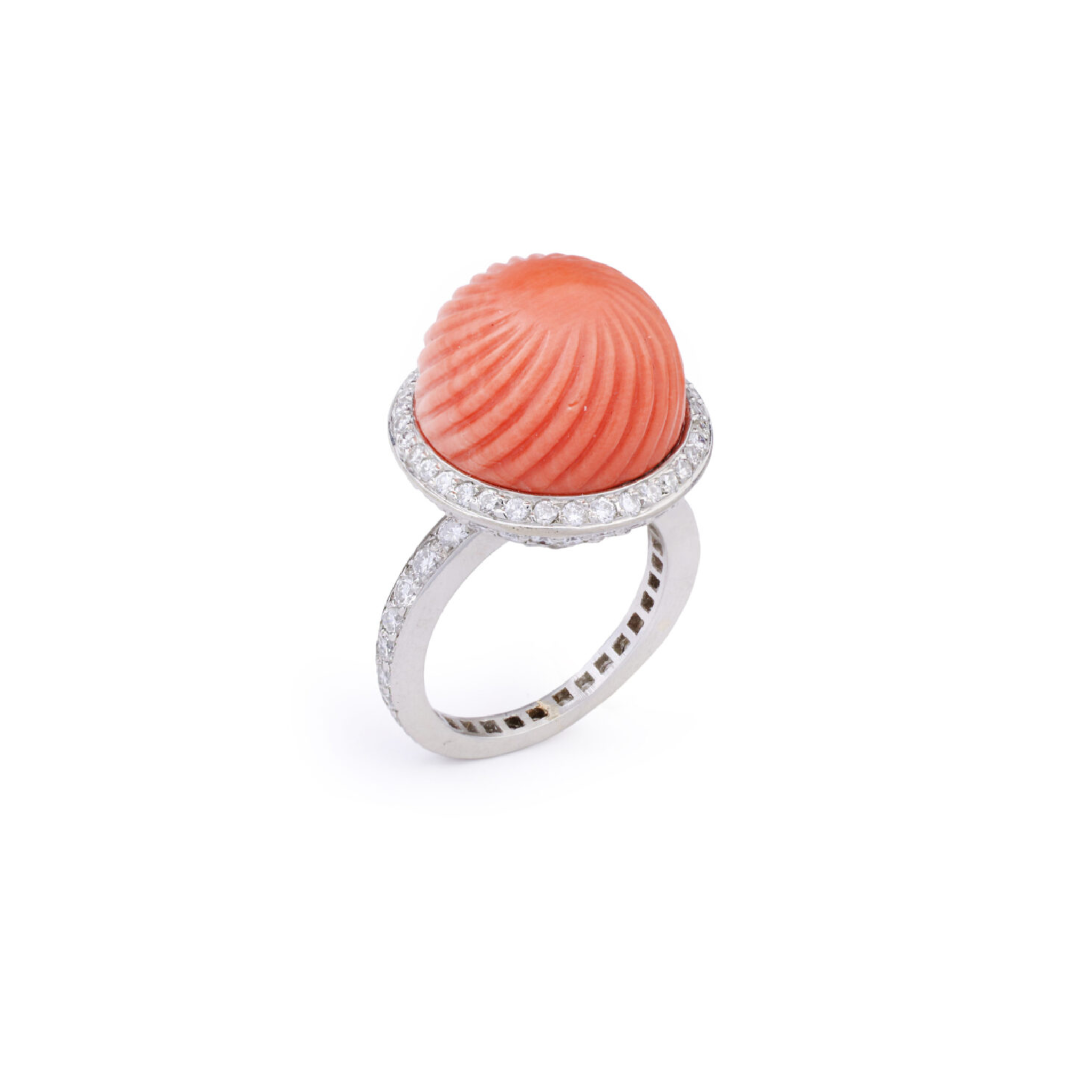 A Cartier Carved Coral and Diamond Ring from the 1950s, showcasing a large ridged coral cabochon dome at its center, surrounded by a band of sparkling pavé diamonds.