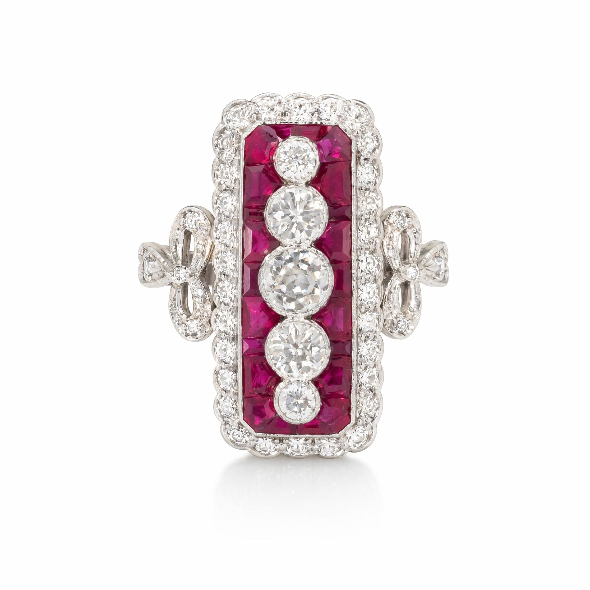 The Ruby and Diamond Ring features four European-cut diamonds in a vertical row, framed by calibré-cut rubies and bordered with smaller diamonds, all set in platinum 18K white gold.