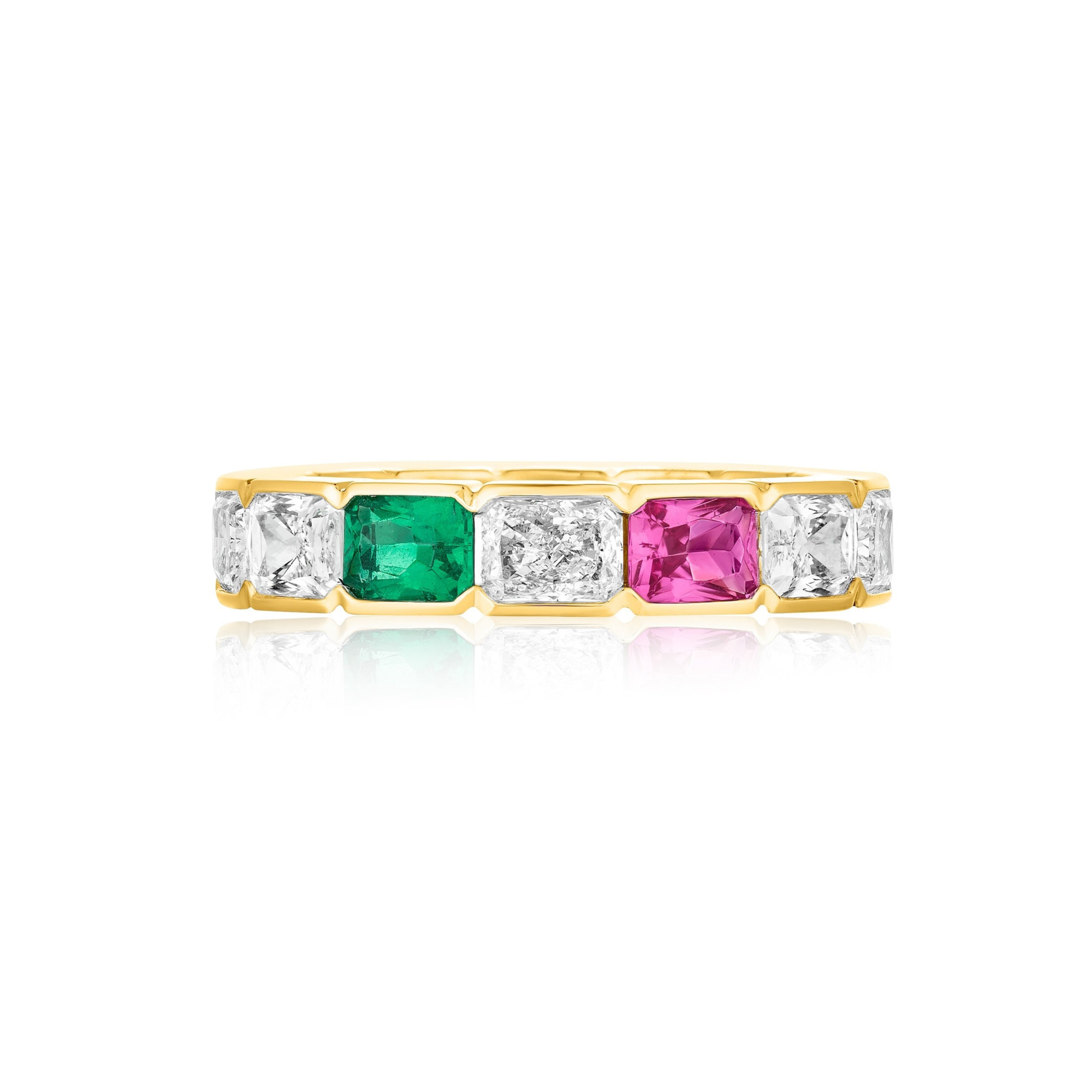 The East-West Half-Bezel Set Radiant Cut Diamond, Emerald, and Sapphire Eternity Band in Yellow Gold features alternating radiant cut diamonds, emeralds, and sapphires on a gold band, shown on a white background with a subtle reflection.