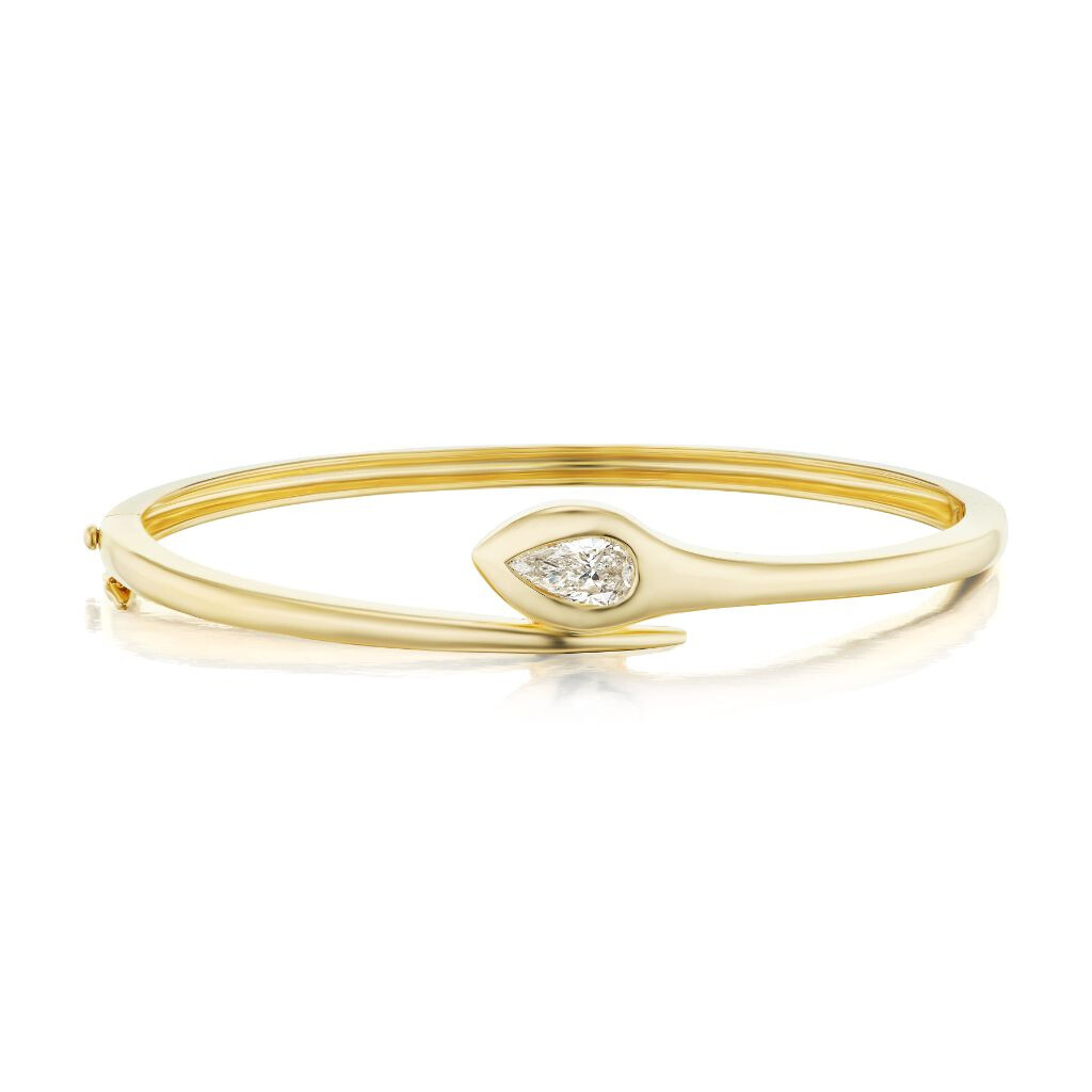 The Serpent Pear Diamond Bangle is crafted in 18K yellow gold with a teardrop-shaped diamond centerpiece, showcasing a modern, minimalist design and polished finish.