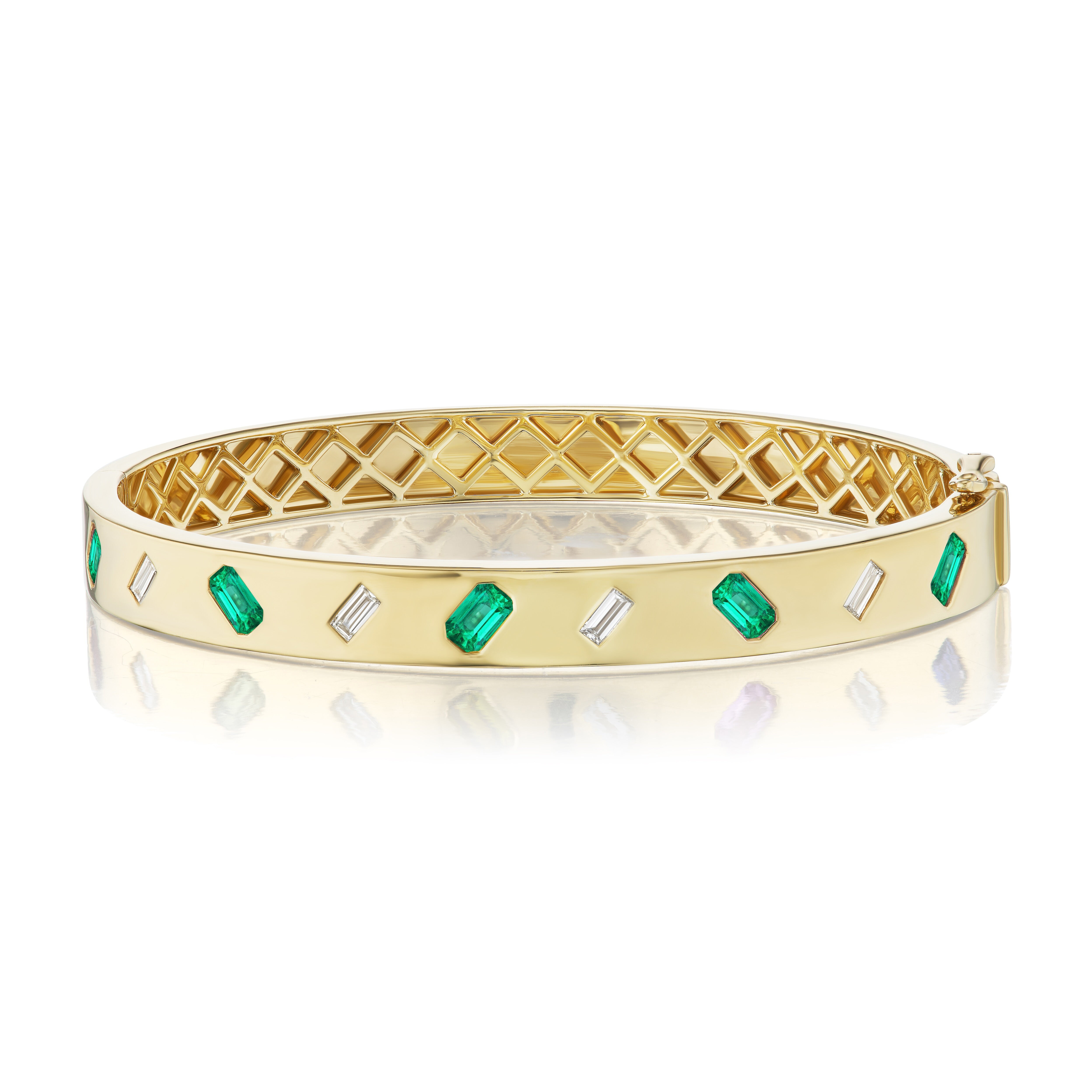 The Alternating Emerald Cut Diamond and Emerald Bangle in Yellow Gold features an 18K yellow gold lattice interior, with alternating rectangular emeralds and diamond-shaped emerald cut diamonds set around the exterior.