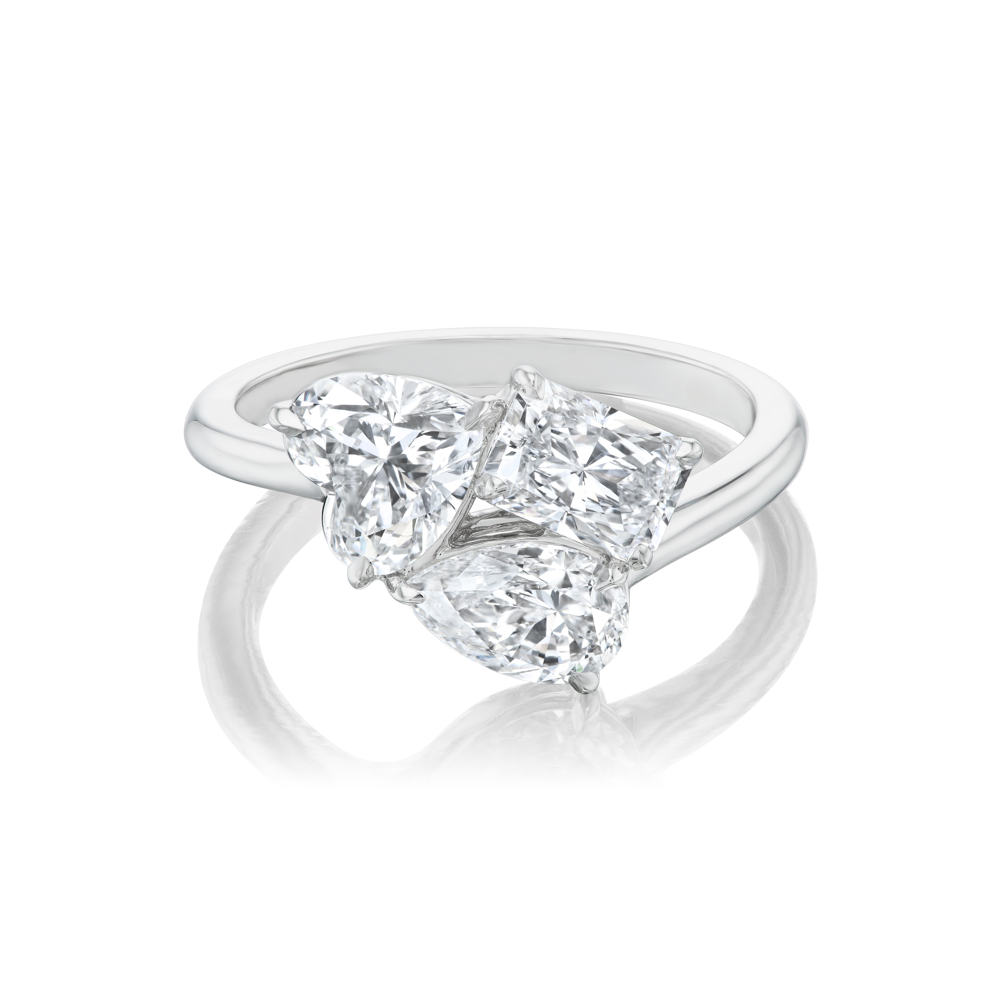 A gorgeous 18K White Gold three stone ring featuring pear shape, heart shape, and radiant cut diamonds set closely together on a sleek, plain band.