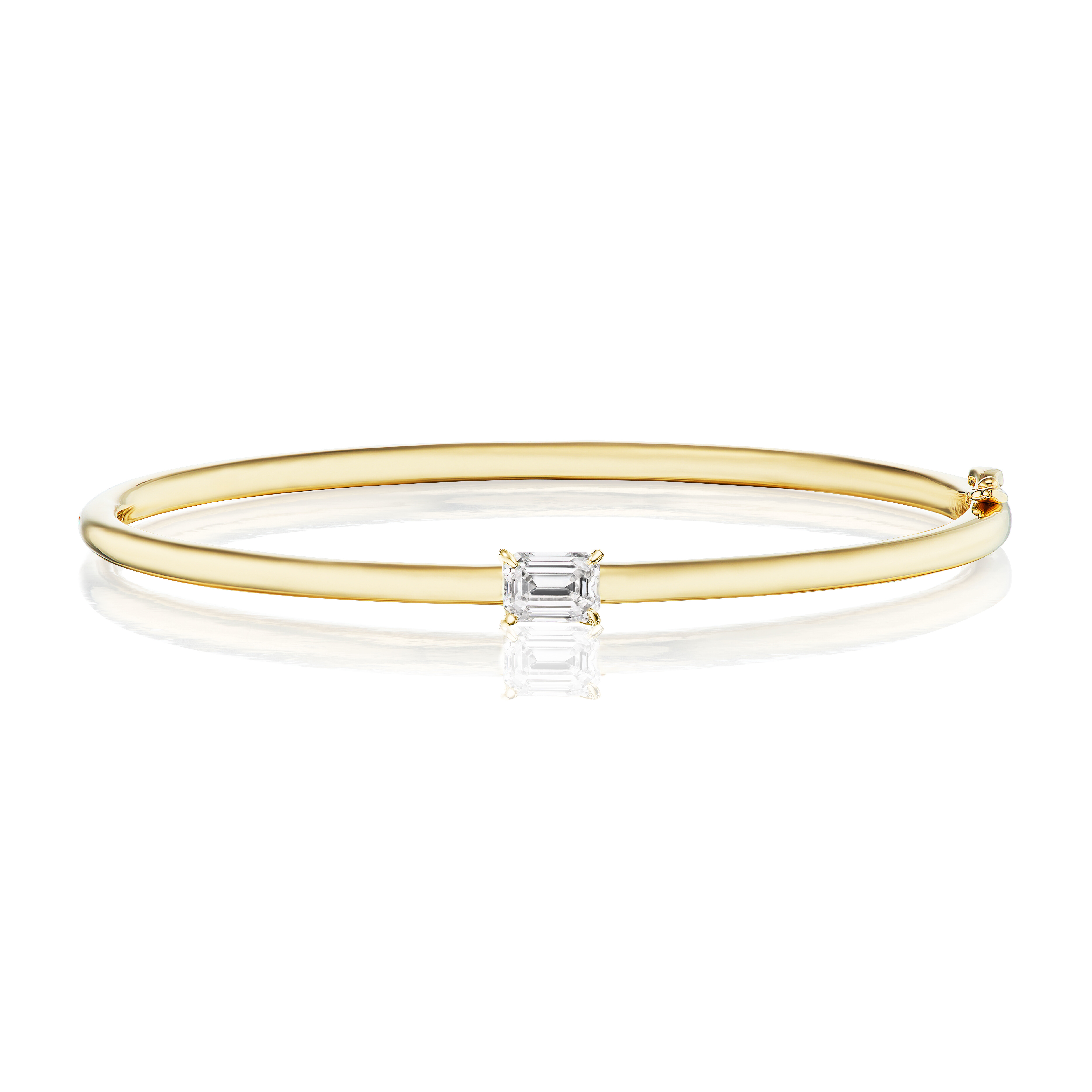 The East-West Set Emerald Cut Diamond Bangle is a slim 18K yellow gold bracelet with a center-set rectangular emerald-cut diamond, shown on a white background.