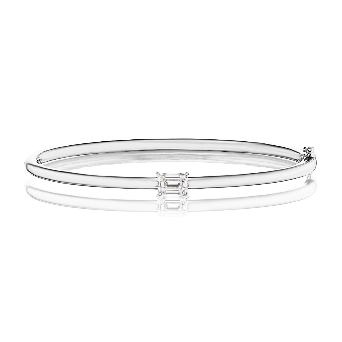 The East-West Set Emerald Cut Diamond Bangle in 18K White Gold showcases a single rectangular, emerald-cut diamond at its center, displayed on a white reflective surface.