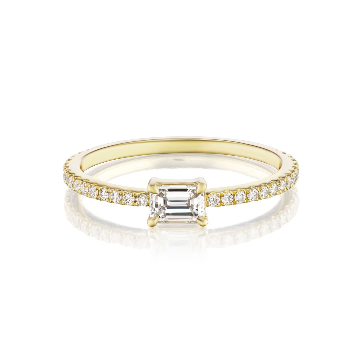 The East-West Set Emerald Cut Diamond Ring with Pavé Band in Yellow Gold features a slim yellow gold band set with round pavé diamonds and a central emerald-cut diamond in prongs, shown on a white background. Perfect for an elegant touch.