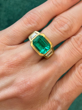 Bezel Set East-West Emerald Cut Emerald Three Stone Ring with Trapezoid Diamond Side Stones in Matte Yellow Gold