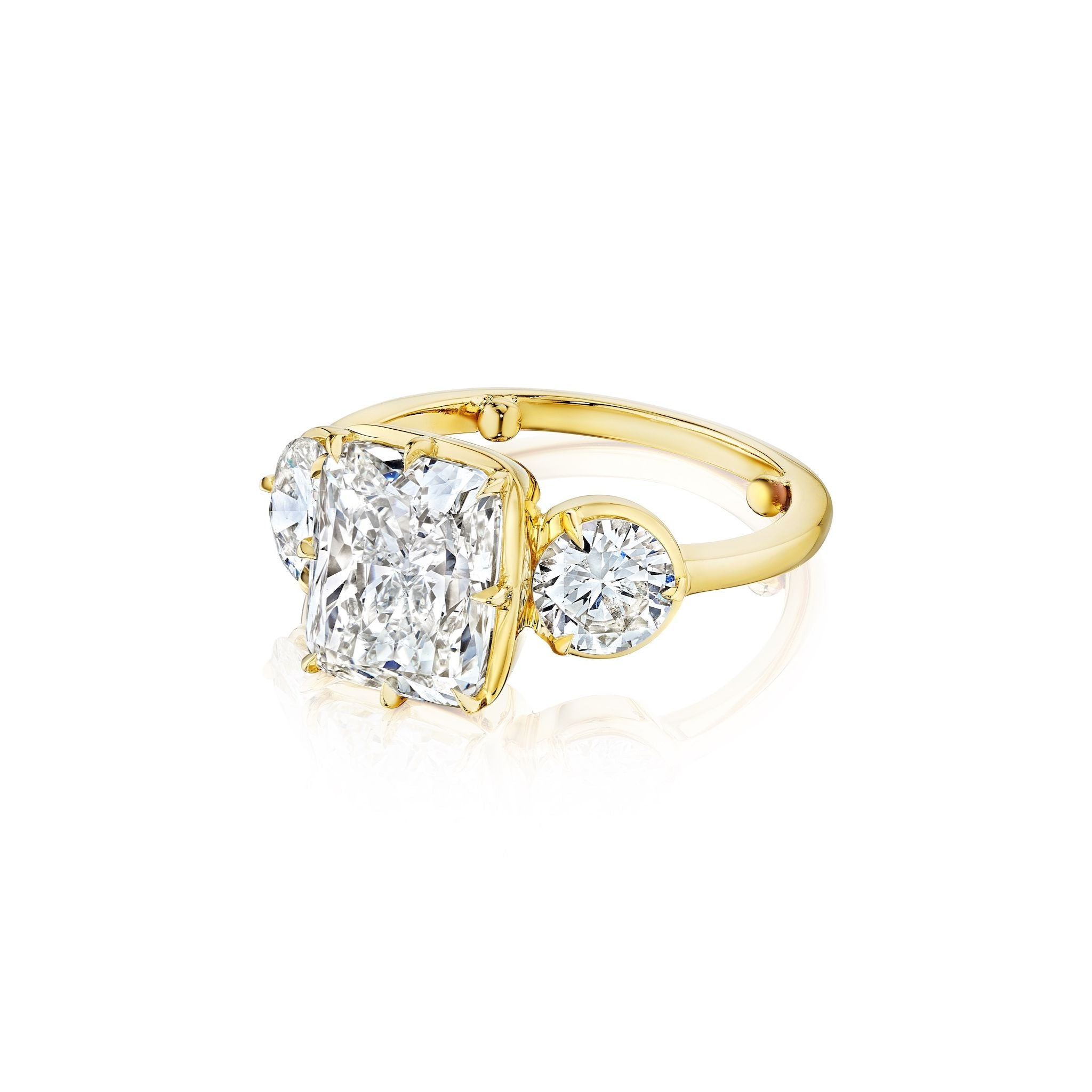 The Collet Set Cushion Cut Diamond Engagement Ring in yellow gold features a large cushion-cut center diamond and round side stones, beautifully displayed on a white background.