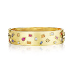 The Bezel Set Multi Shape Mixed Stone Bangle in Yellow Gold features round, square, oval, and baguette stones beautifully scattered across its wide, polished gold surface.