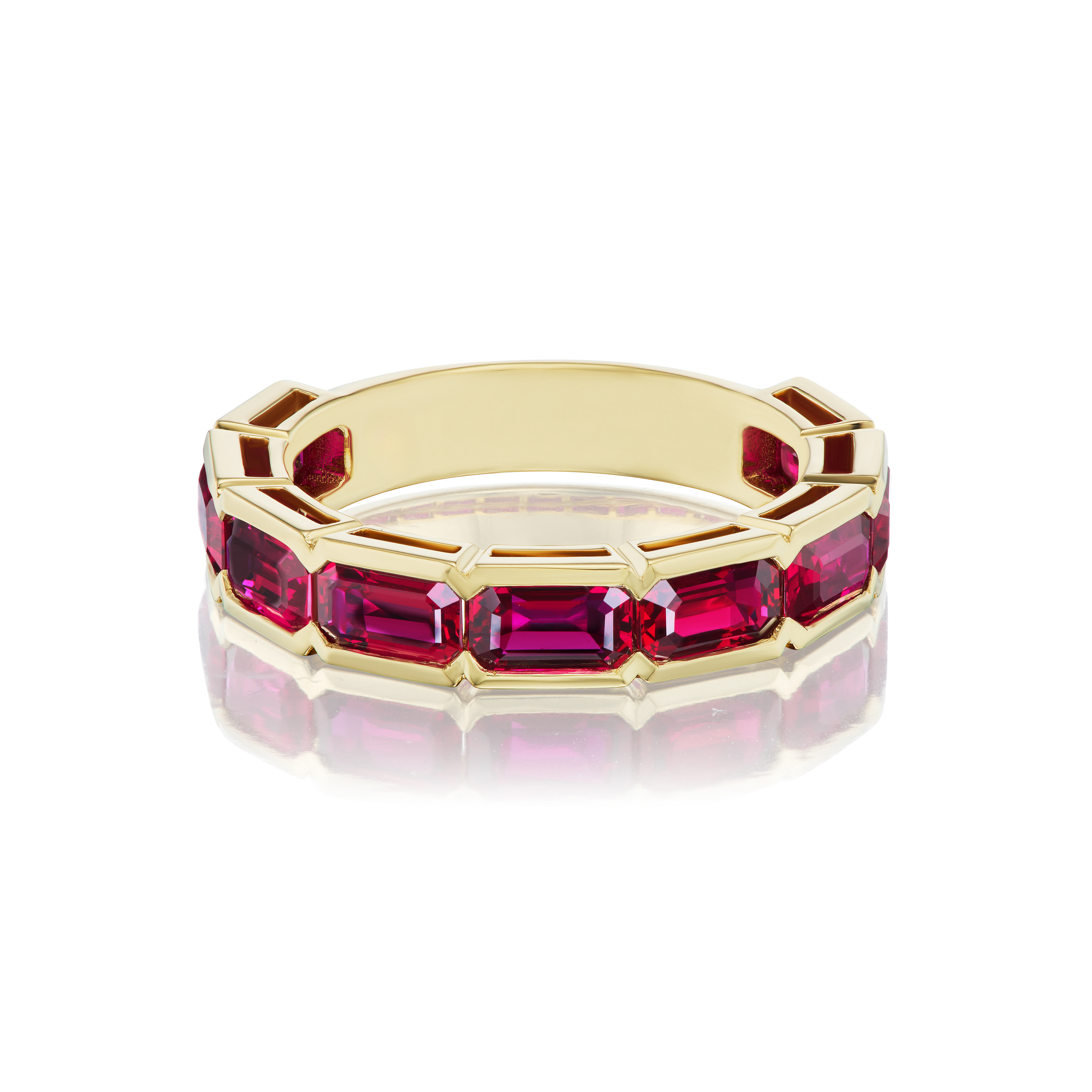 The Bezel Set East-West Emerald Cut Ruby Half-Eternity Band in Yellow Gold features emerald-cut rubies in a bezel setting, photographed on a white background with a slight reflection below.