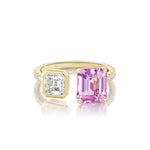The Toi et Moi Pavé Ring features a square emerald cut diamond paired with an emerald cut pink sapphire, all set in 18k yellow gold with a band elegantly accented by pavé-set white stones.