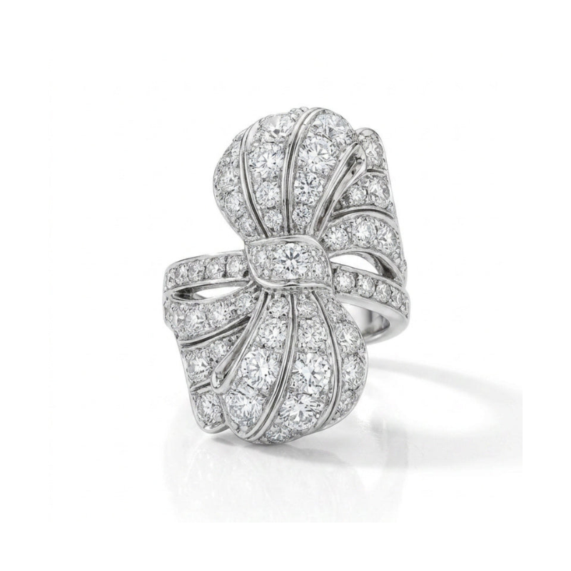 The Diamond Ring is a platinum band inspired by 1930s jewelry, featuring a bow design encrusted with old European diamonds for a sparkling, elegant look. Presented against a plain white background.