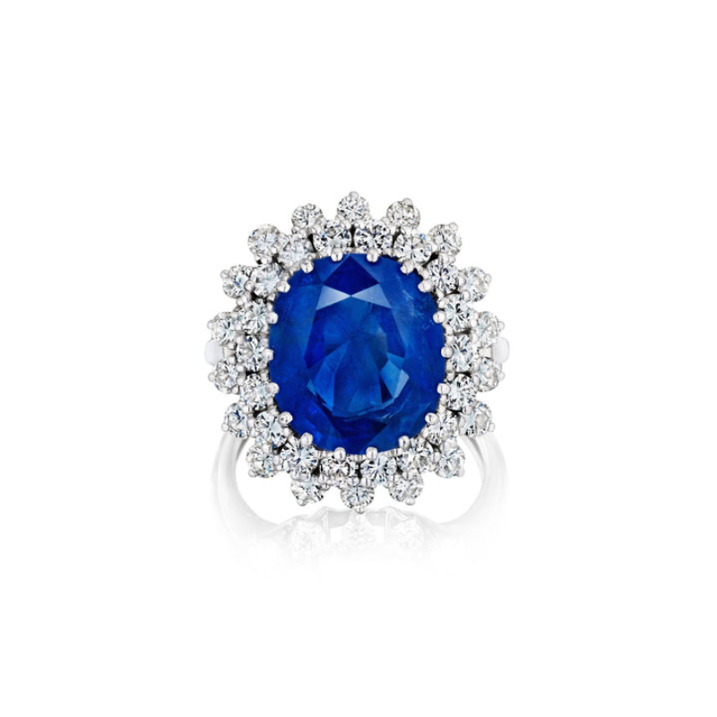 The Sapphire and Diamond Ring features a large oval Burmese sapphire at the center, encircled by two rows of sparkling round white diamonds in a floral halo on a silver band.