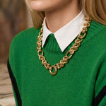 A woman with blonde hair wears a bright green sweater over a white collared shirt, accessorized with the Gold Link Necklace. Her face is partially out of frame.