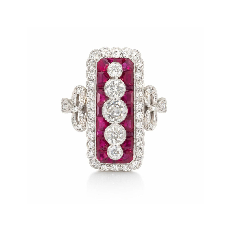 The Ruby and Diamond Ring features a rectangular design with central old European-cut diamonds, surrounded by calibré-cut rubies and framed by small white diamonds on a platinum and 18K white gold band with decorative side accents.