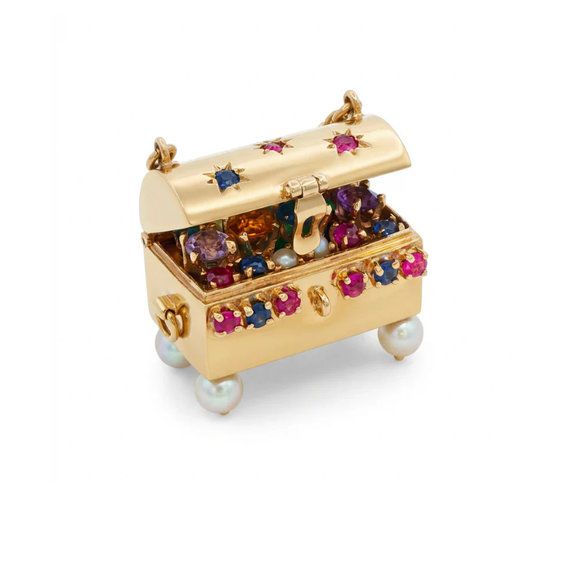 The Gold and Gem-Set Charm is a small 14K gold treasure chest jewelry box decorated with ruby, sapphire, and pearls, sitting open on four pearl feet and filled with sparkling jewels against a white background.