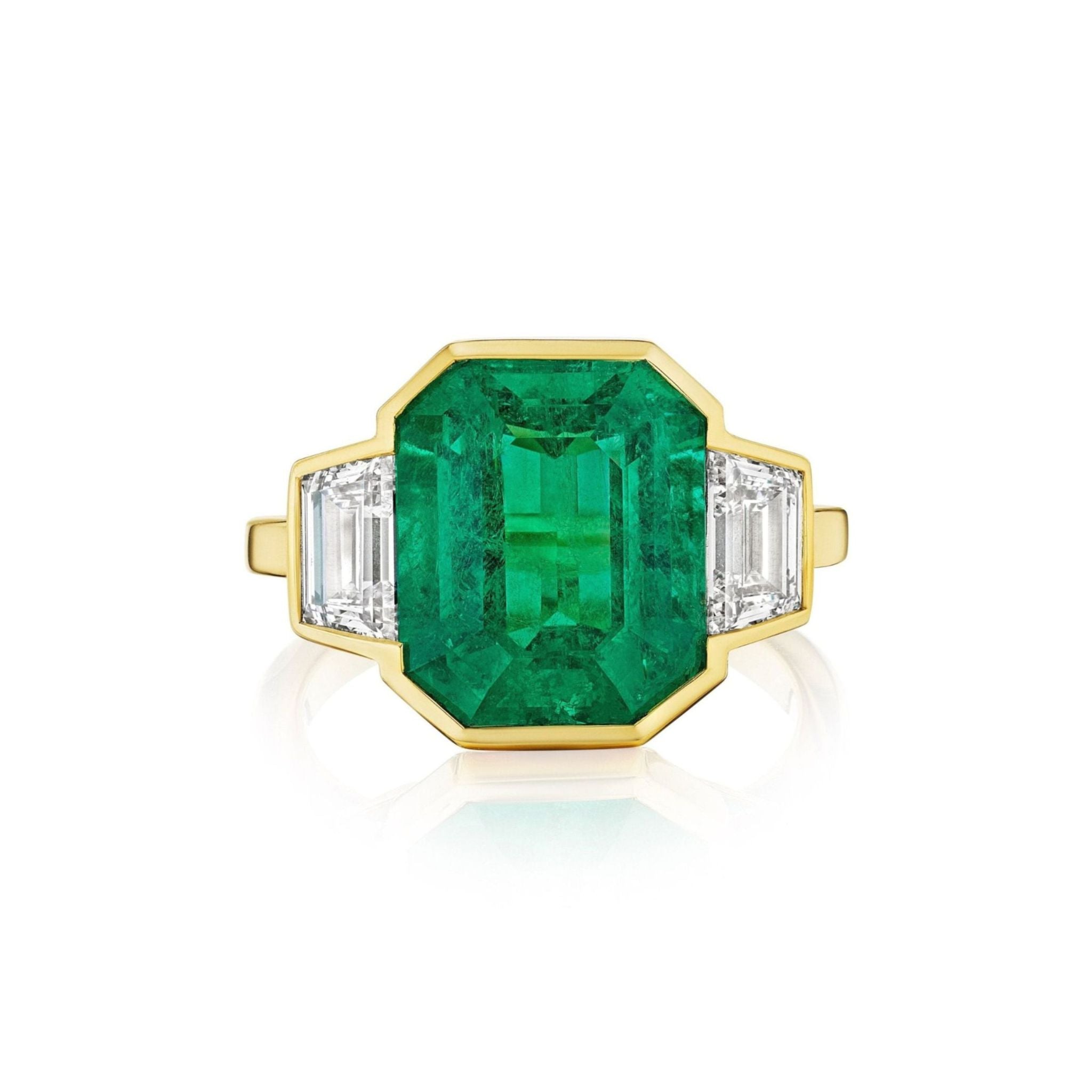 Introducing the Half Bezel Set Emerald Cut Emerald Engagement Ring with Trapezoid Diamond Side Stones in Yellow Gold—an exquisite ring crafted in 18k yellow gold, showcasing a striking emerald-cut green emerald center stone accented by two elegant trapezoid diamonds on each side.
