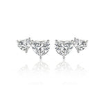 The Duo Studs with Heart Diamonds are stud earrings featuring a trio of clear gemstones—one round and two heart-shaped diamonds—arranged symmetrically against a white background.