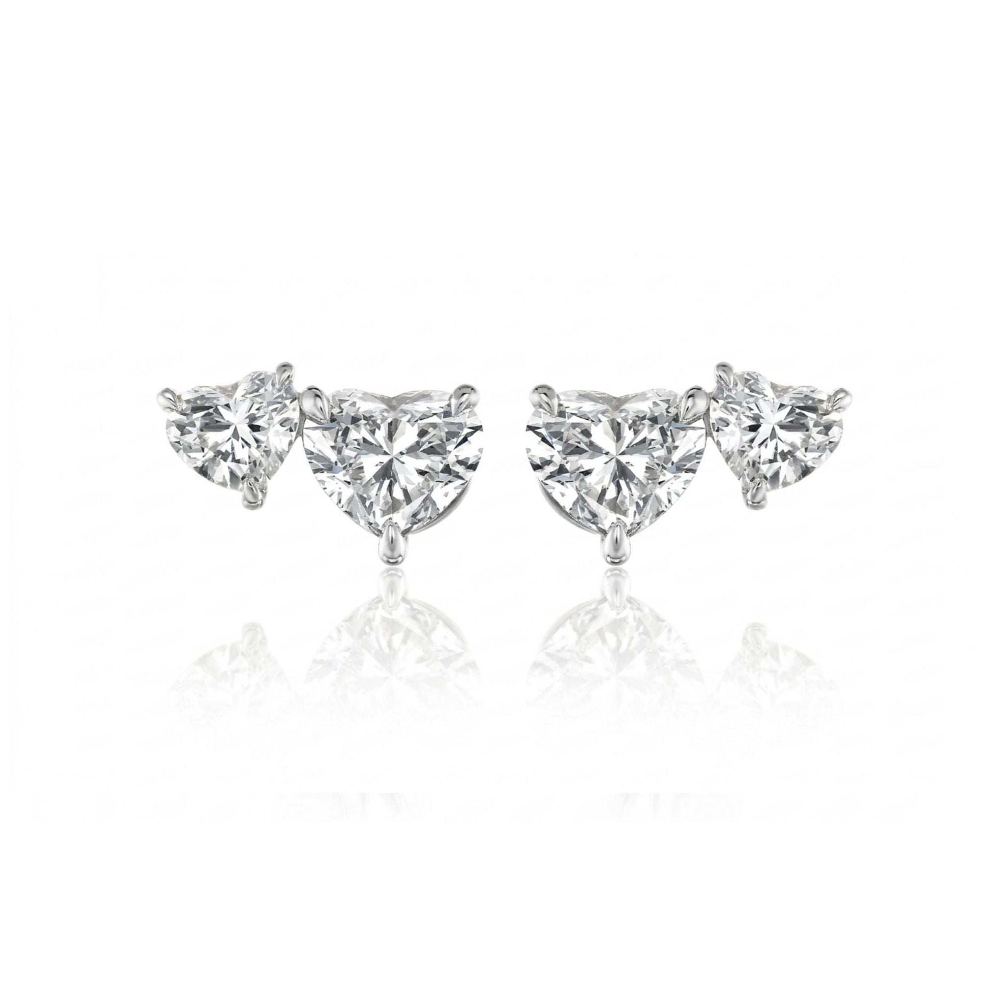 The Duo Studs with Heart Diamonds are stud earrings featuring a trio of clear gemstones—one round and two heart-shaped diamonds—arranged symmetrically against a white background.