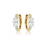 The Pavé Huggies with Oval Shape Diamond are 18k gold hoop earrings showcasing a large oval diamond centerpiece and a pavé row of smaller diamonds along the front, displayed against a white background.