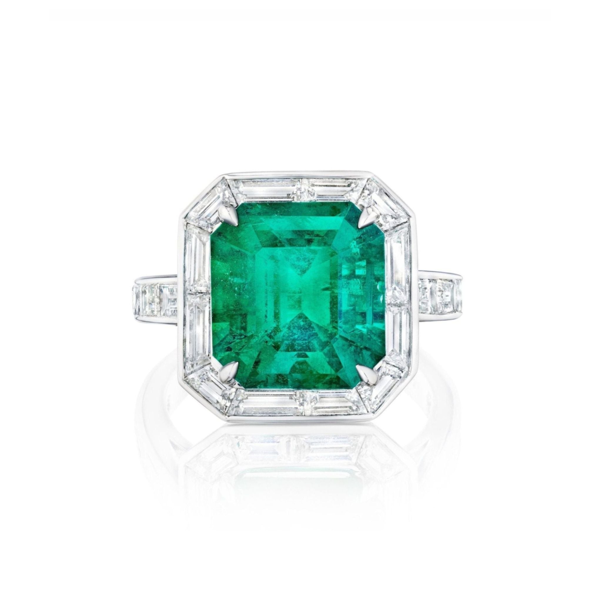 The Mosaic Asscher Cut Emerald and Baguette Diamond Cocktail Ring in Platinum showcases a striking Asscher cut emerald at its center, elegantly framed by sparkling baguette diamonds, all set against a white background.