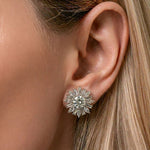 A close-up of a woman's ear showcases the Snowflake Marquise and Baguette Diamond Ear Jackets in white gold. Her straight blond hair is tucked behind her ear, drawing attention to the sparkling diamond jewelry.