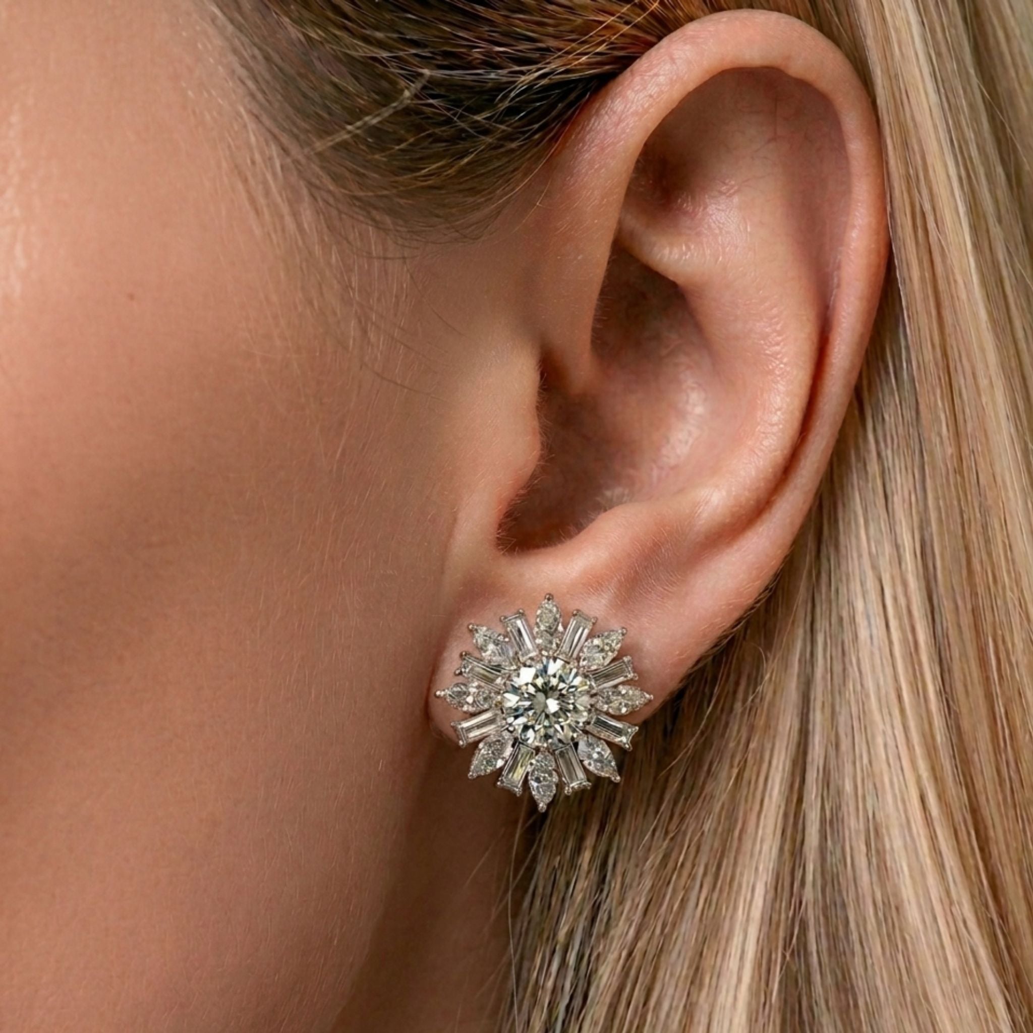A close-up of a woman's ear showcases the Snowflake Marquise and Baguette Diamond Ear Jackets in white gold. Her straight blond hair is tucked behind her ear, drawing attention to the sparkling diamond jewelry.