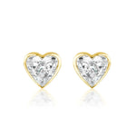 The Bezel Set Diamond Heart Studs showcase G color diamonds in a heart shape, set in 18k gold and displayed on a white background.