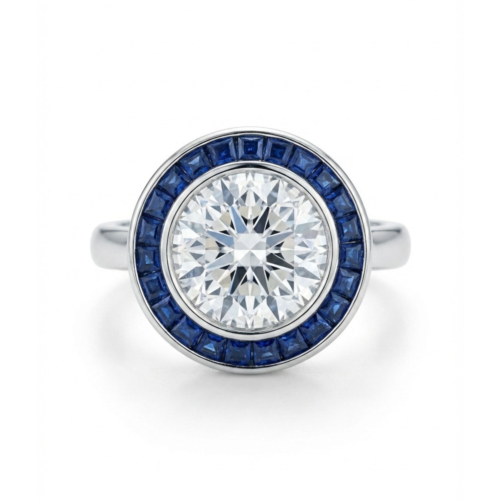The Round Brilliant Diamond with Channel Set Sapphire Halo Ring features a large round diamond at the center, encircled by square-cut blue sapphires in a stunning halo design.