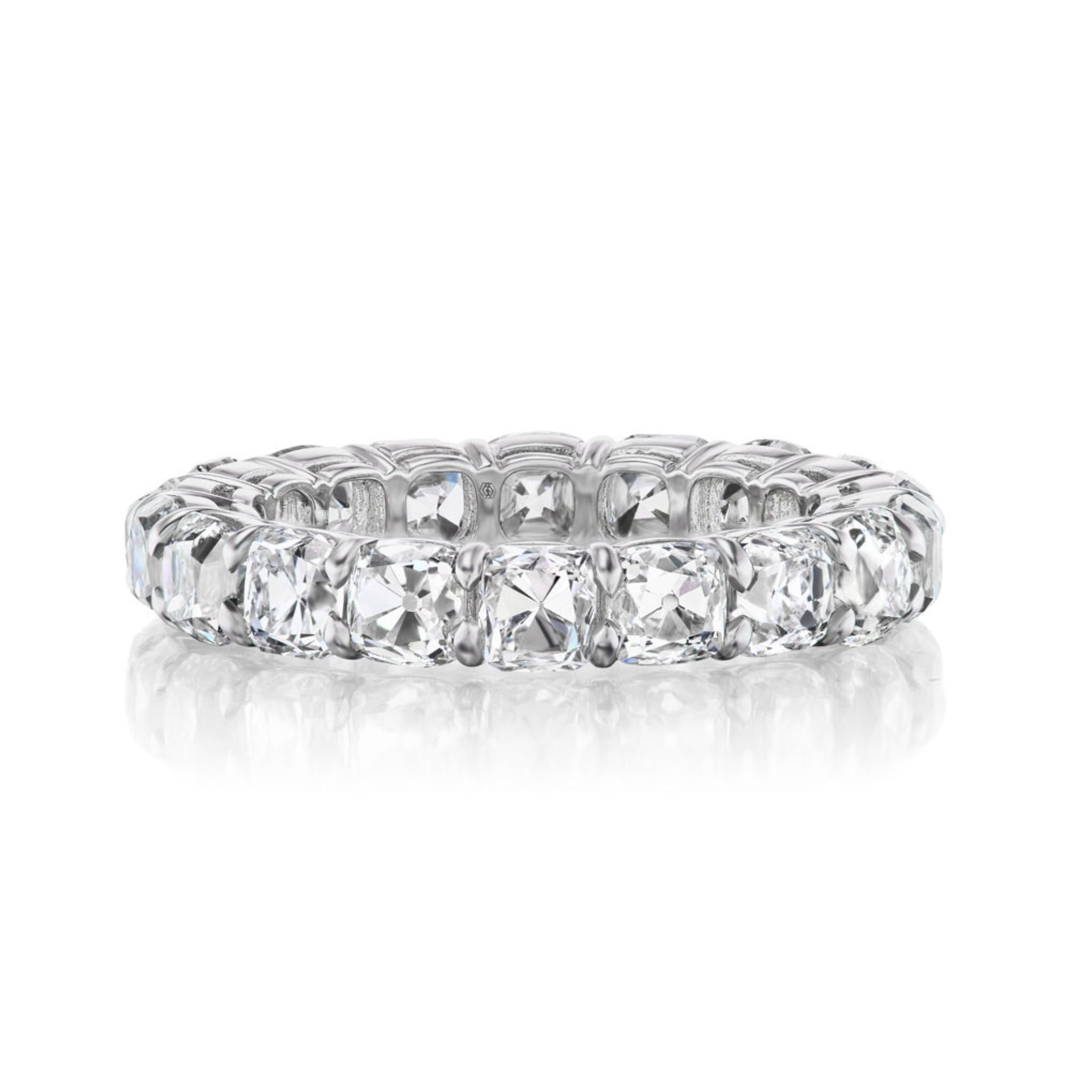 The Old Mine Cut Diamond Eternity Band features a continuous row of cushion-cut diamonds set closely together, showcased on a white reflective surface.
