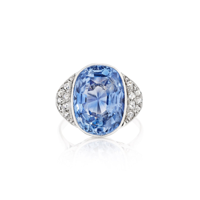 The Sapphire and Diamond Ring showcases a large oval-cut Ceylon sapphire at the center, accented by clusters of rose-cut diamonds on each side, all set in a silver band.