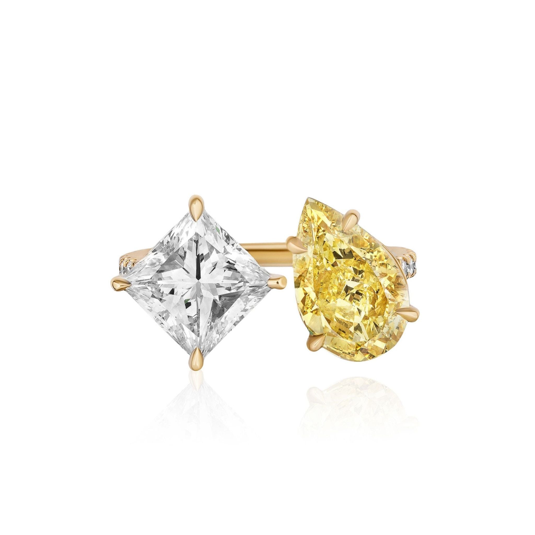 The Toi et Moi Pavé Ring showcases a white princess cut diamond and a fancy yellow pear-shaped diamond, each secured with four prongs, displayed on a white background.