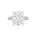 The Cushion Cut Diamond Engagement Ring with Pavé Band features a large center stone secured by four prongs and a pavé band encrusted with small diamonds, beautifully displayed against a white background.
