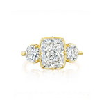 A Collet Set Cushion Cut Diamond Engagement Ring with Round Side Stones in Yellow Gold is displayed against a white background, featuring a cushion-cut diamond at the center set in 18k yellow gold and complemented by round diamond side stones on each side.