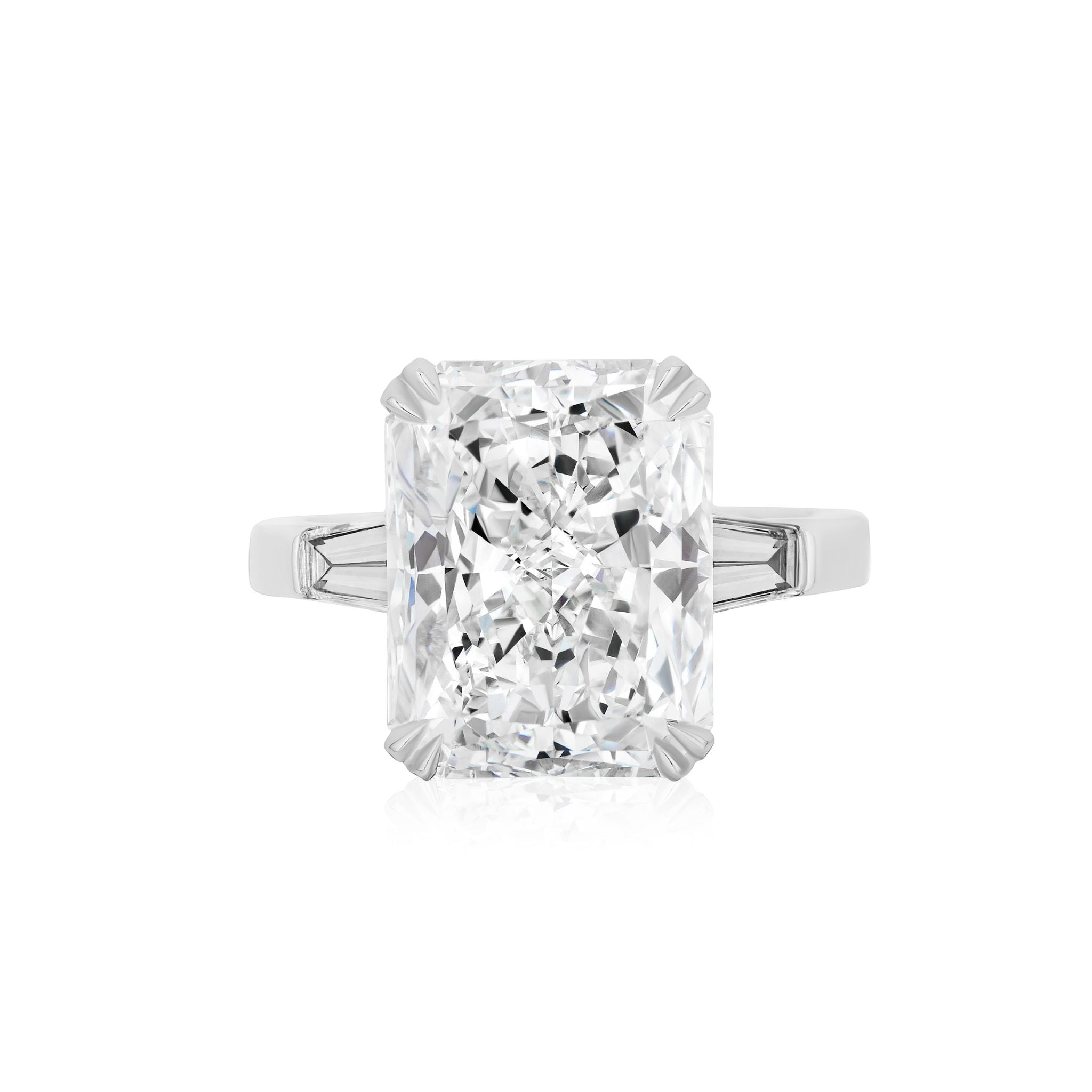The Radiant Cut Diamond Engagement Ring with Tapered Baguettes features a rectangular radiant-cut center diamond flanked by tapered baguette side stones, set on a sleek, polished platinum band and displayed against a white background.