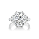 A radiant cut diamond engagement ring with a bezel setting and epaulette side stones, set in a sleek platinum band and displayed against a white background.