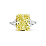 A Fancy Yellow Radiant Cut Diamond Engagement Ring featuring tapered baguette side stones, set on a sleek white metal band.